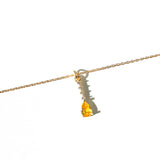 The Sunspill Necklace by LLUME Jewelry showcases a delicate gold multi-length chain with a yellow teardrop-shaped gemstone pendant, accented by small clear stones set above it, and is displayed against a white background.