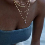 Close-up of a person wearing multiple necklaces with a blurred background