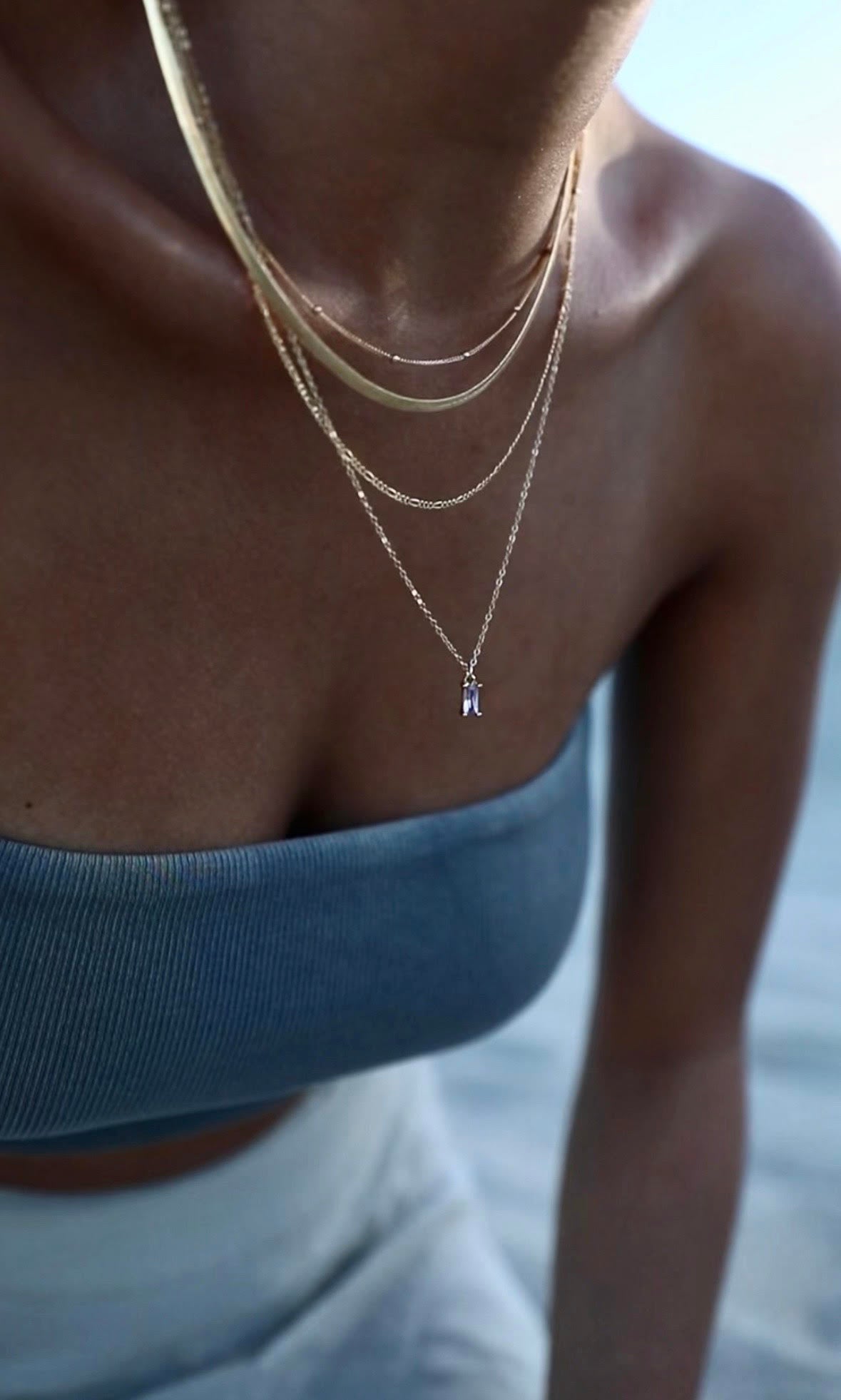 Close-up of a person wearing multiple necklaces with a blurred background